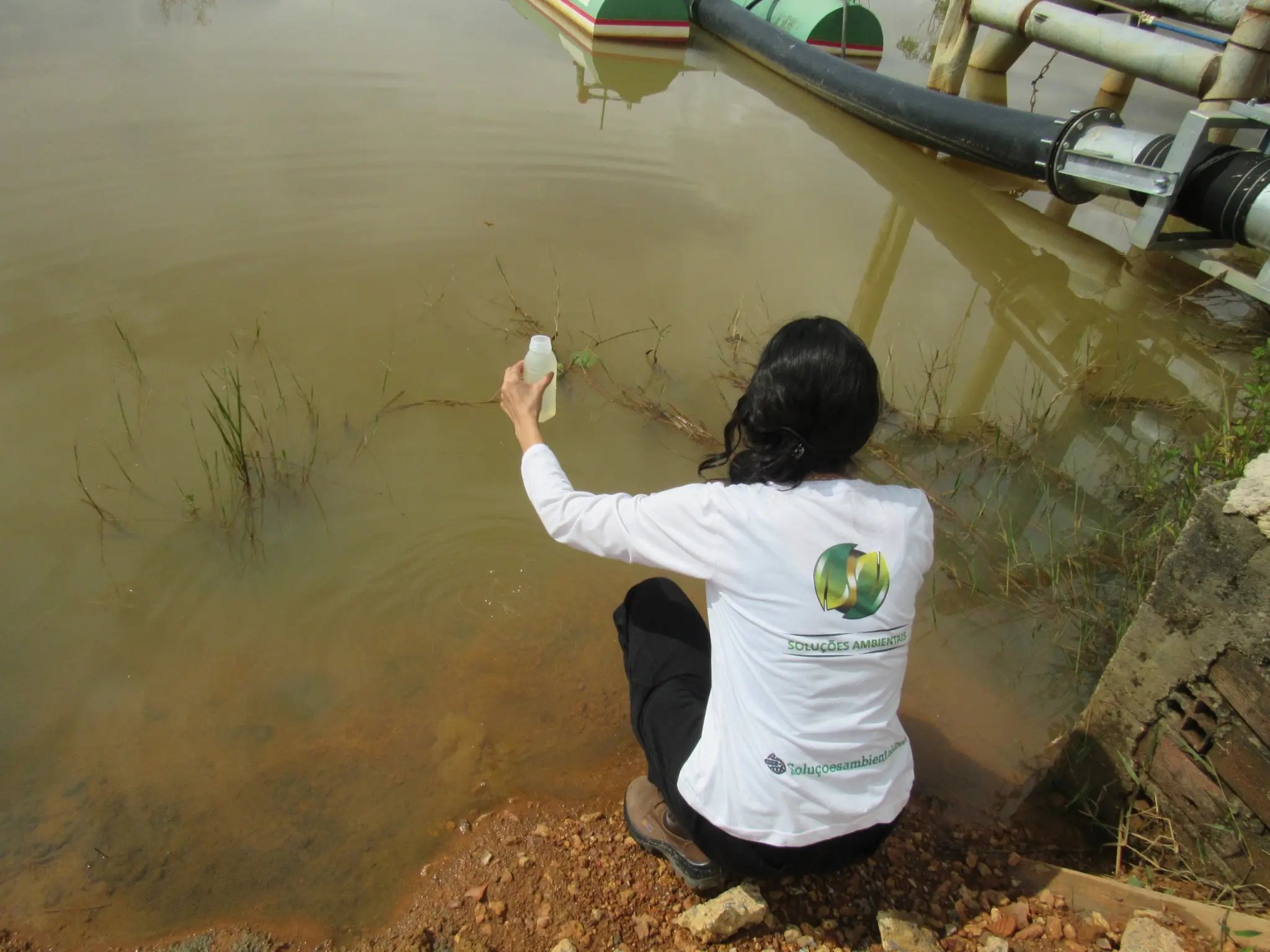Profissional da Soluções Ambientais realizando coleta de amostra de água em campo